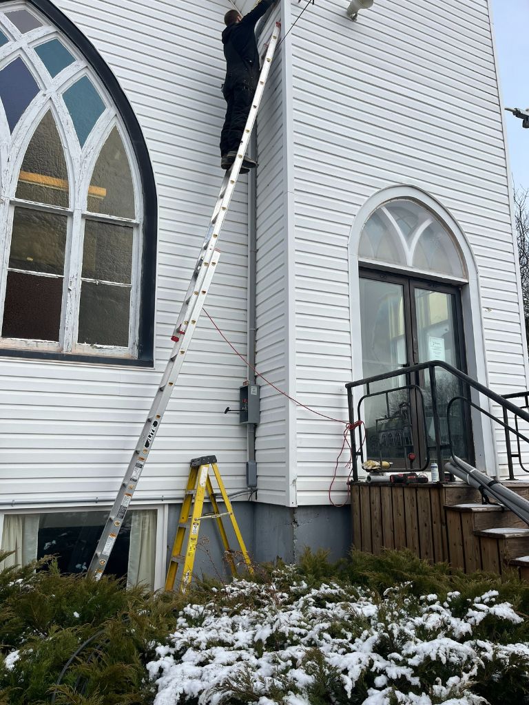 a man on a yellow ladder leaning against a white building