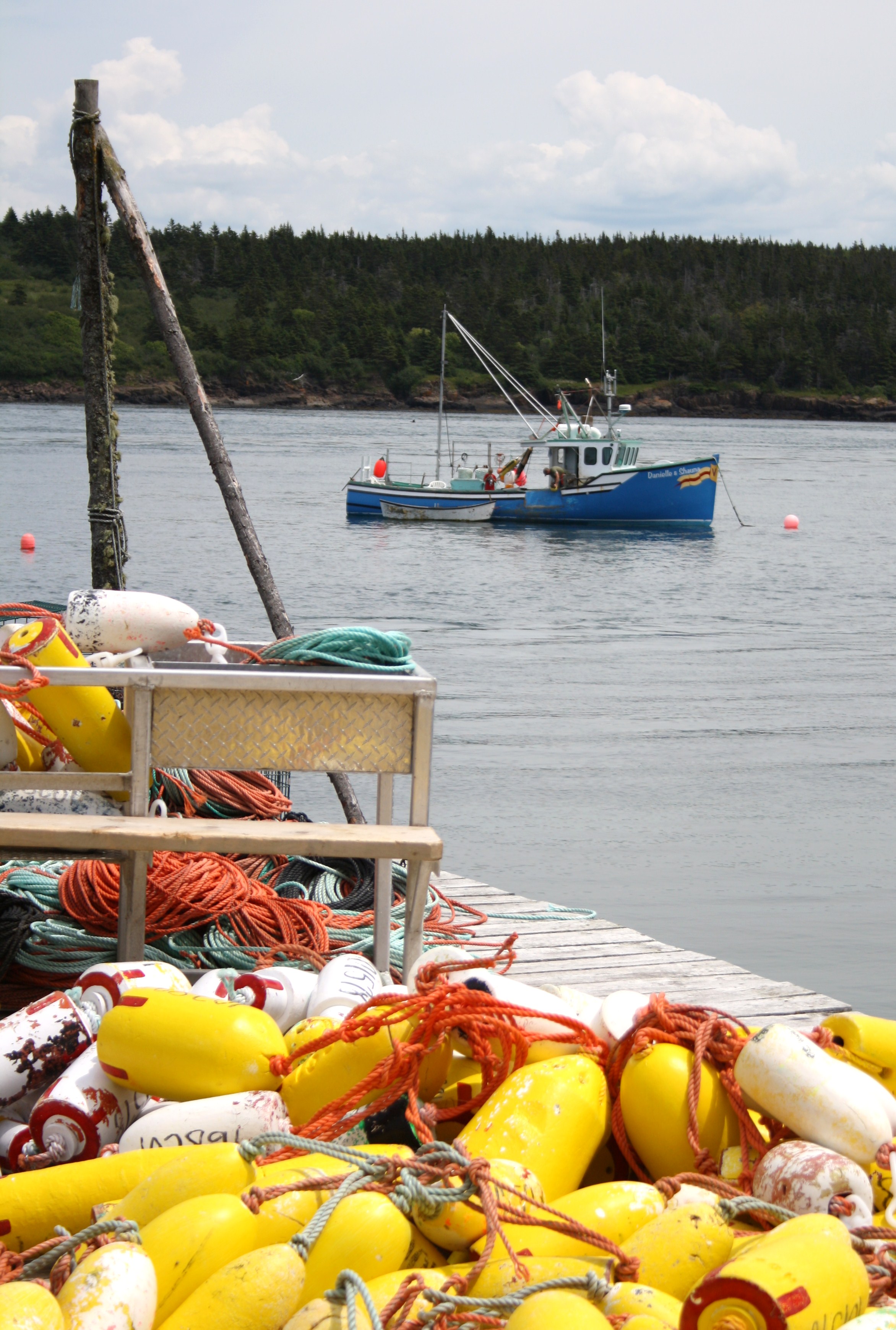 a blue fishing boat with orange buoys in the foreground.