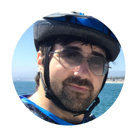 Circular headshot of Ben wearing sunglasses and a bike helmet and smiling