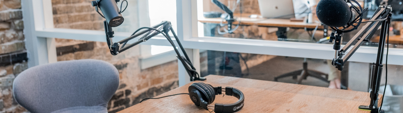 two sets of headphones and two recording microphones sit on a table
