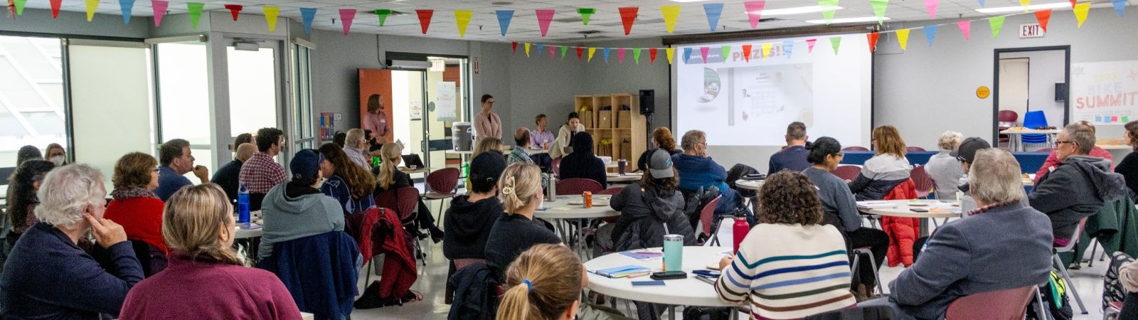 people seated at tables in a large room in a workshop setting