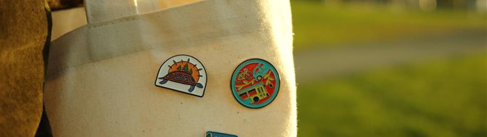 three badges pinned to a tote bag