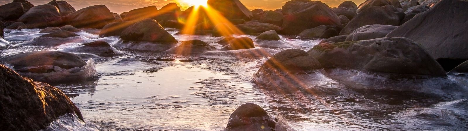 sun rising over a rocky ocean shore