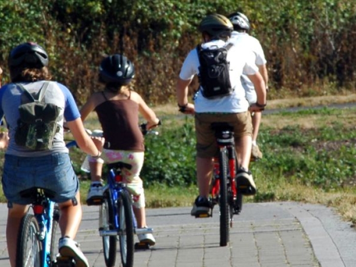 six people ride bicycles down a paved pathway