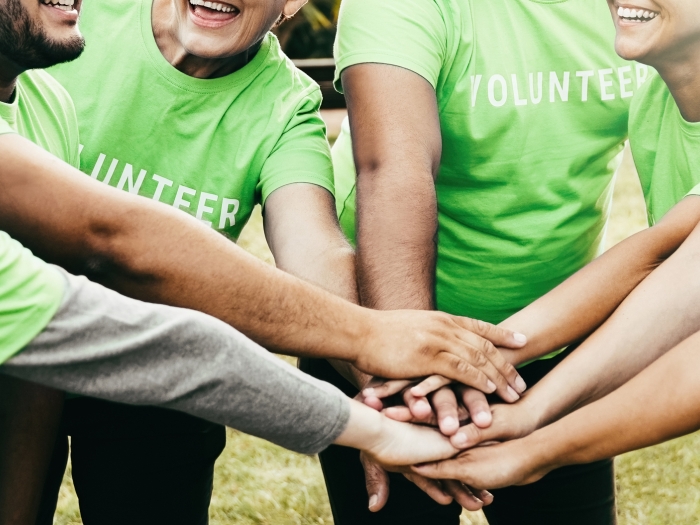 eight people with their arms in a circle wearing lime green tshirts.