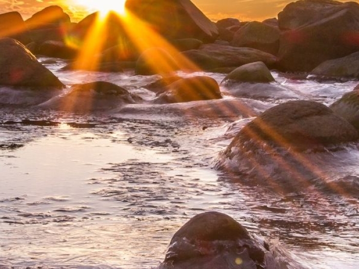 sun rising over a rocky ocean shore