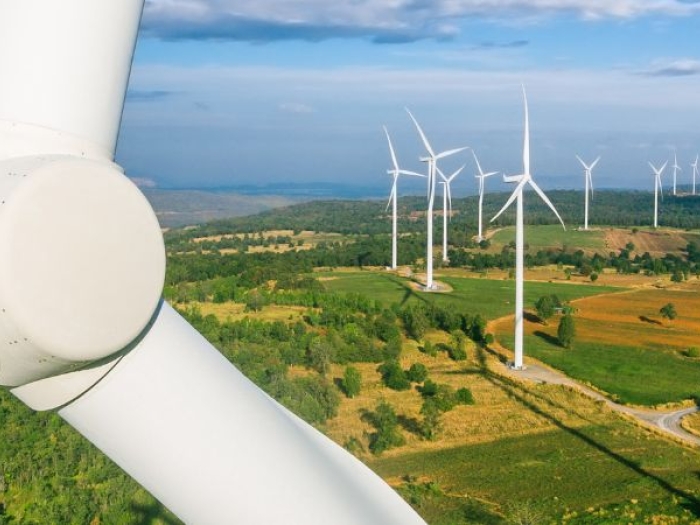 A field with several wind turbines under a blue sky