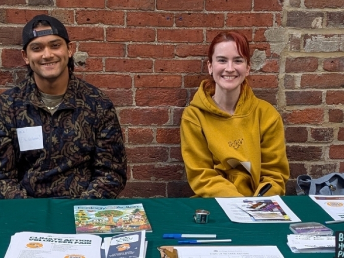 Two young people sitting at an EAC volunteer table, smiling